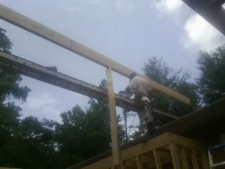 Carpenter setting a ridge beam over a new addition frame — Ice Dam Removal by Roofing Brothers in Queens Village