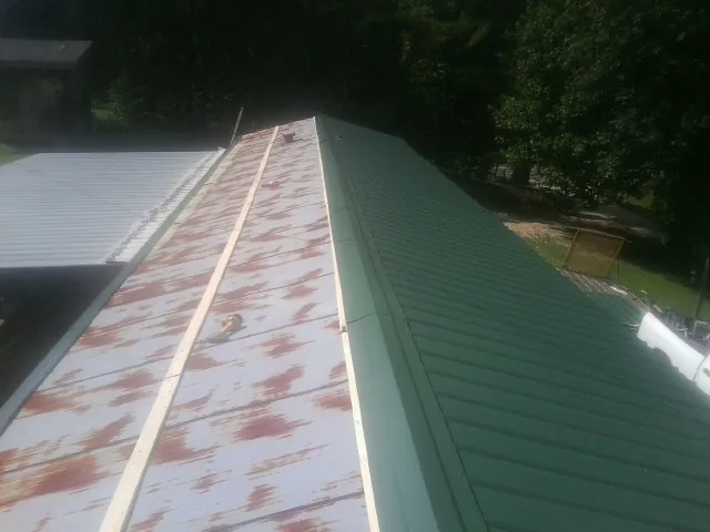 Old rusted panels beside newly installed green metal roofing — Wind Damage Roof Repair by Roofing Brothers in Queens Village
