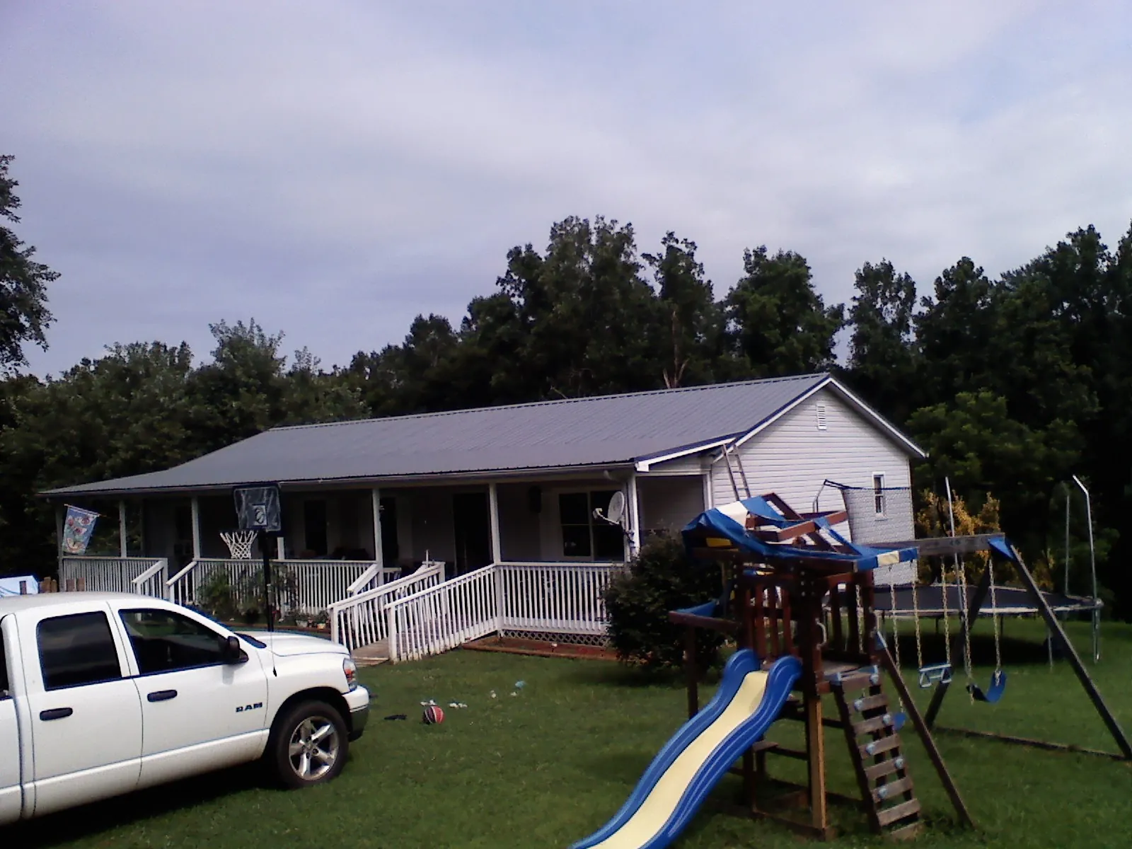 Dark metal roof on a country home with a full length front porch in Queens Village