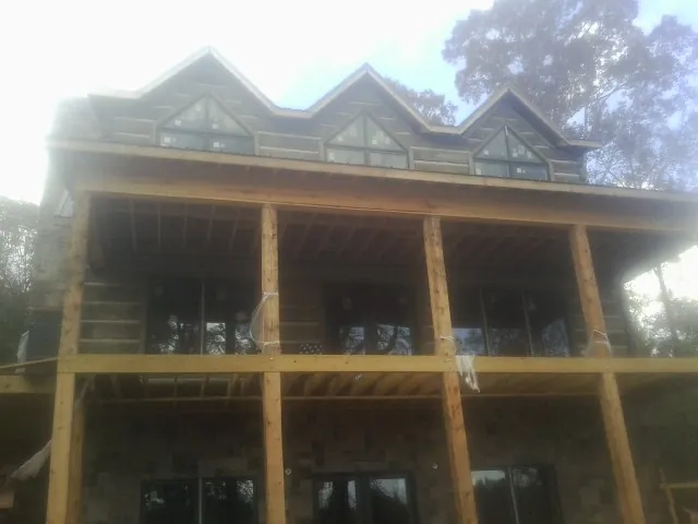 Dormers and porch framing on a large log home under construction — Roof Coating work by our crew in Queens Village