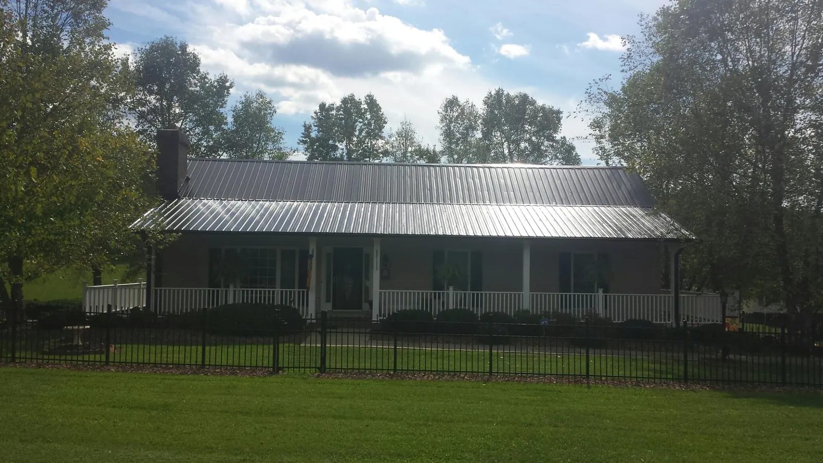 Gray metal roof on a brick ranch with a full width front porch — Gutter Guard Installation work by our crew in Queens Village