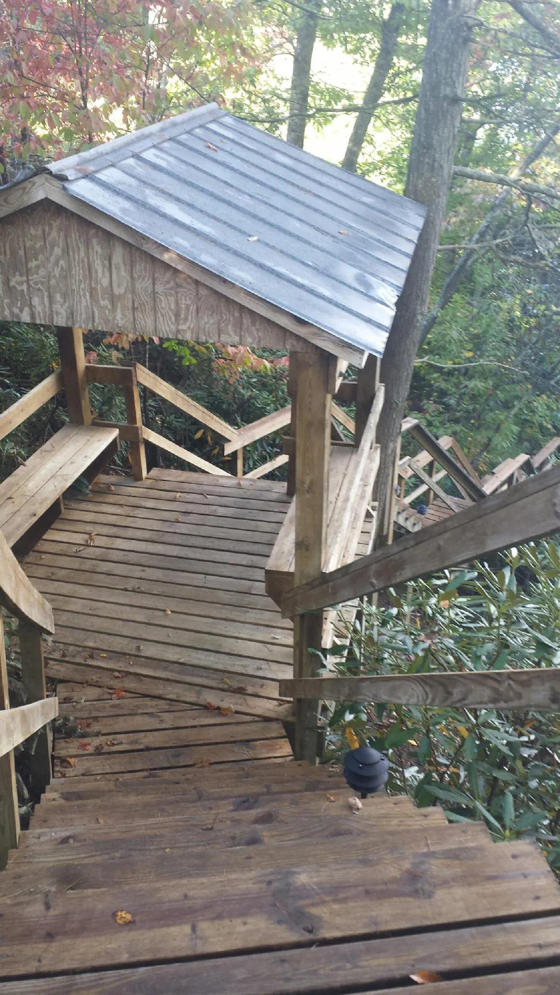 Metal roofed shelter over wooden steps on a wooded walkway — Skylight Repair & Installation work by our crew in Queens Village