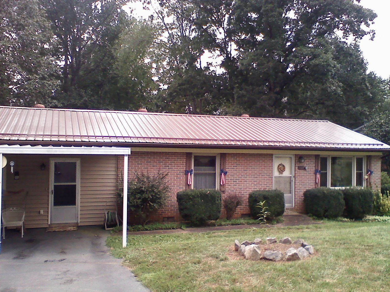 Bronze metal roof and carport on a brick ranch home — Roof Repair work by our crew in Queens Village