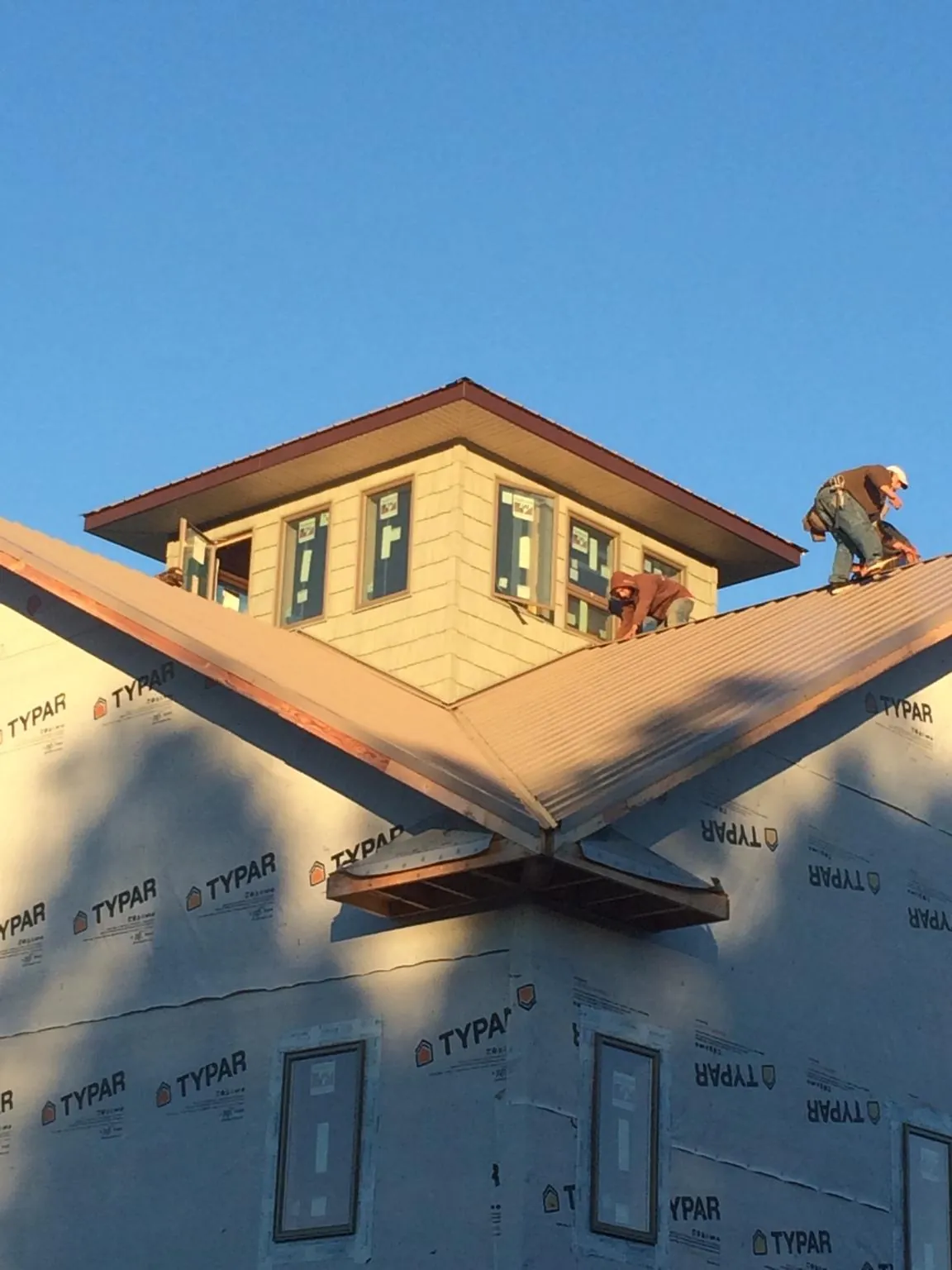 Roofers working around a rooftop cupola on a new metal roof at sunset — Roof Waterproofing in Queens Village by Roofing Brothers